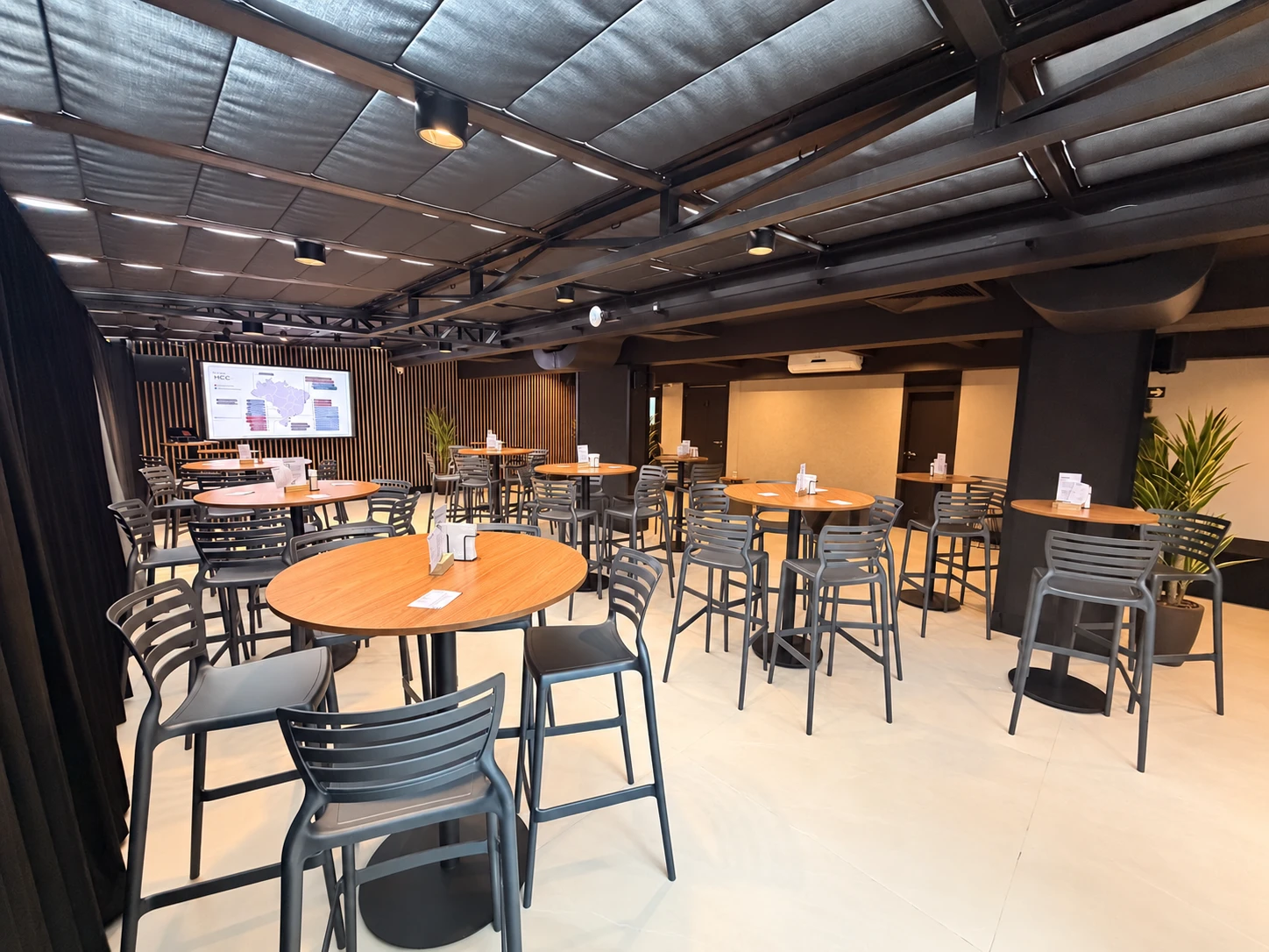 Lounge 3 nas Mercês, Curitiba, com mesas altas, cadeiras e TV para eventos corporativos