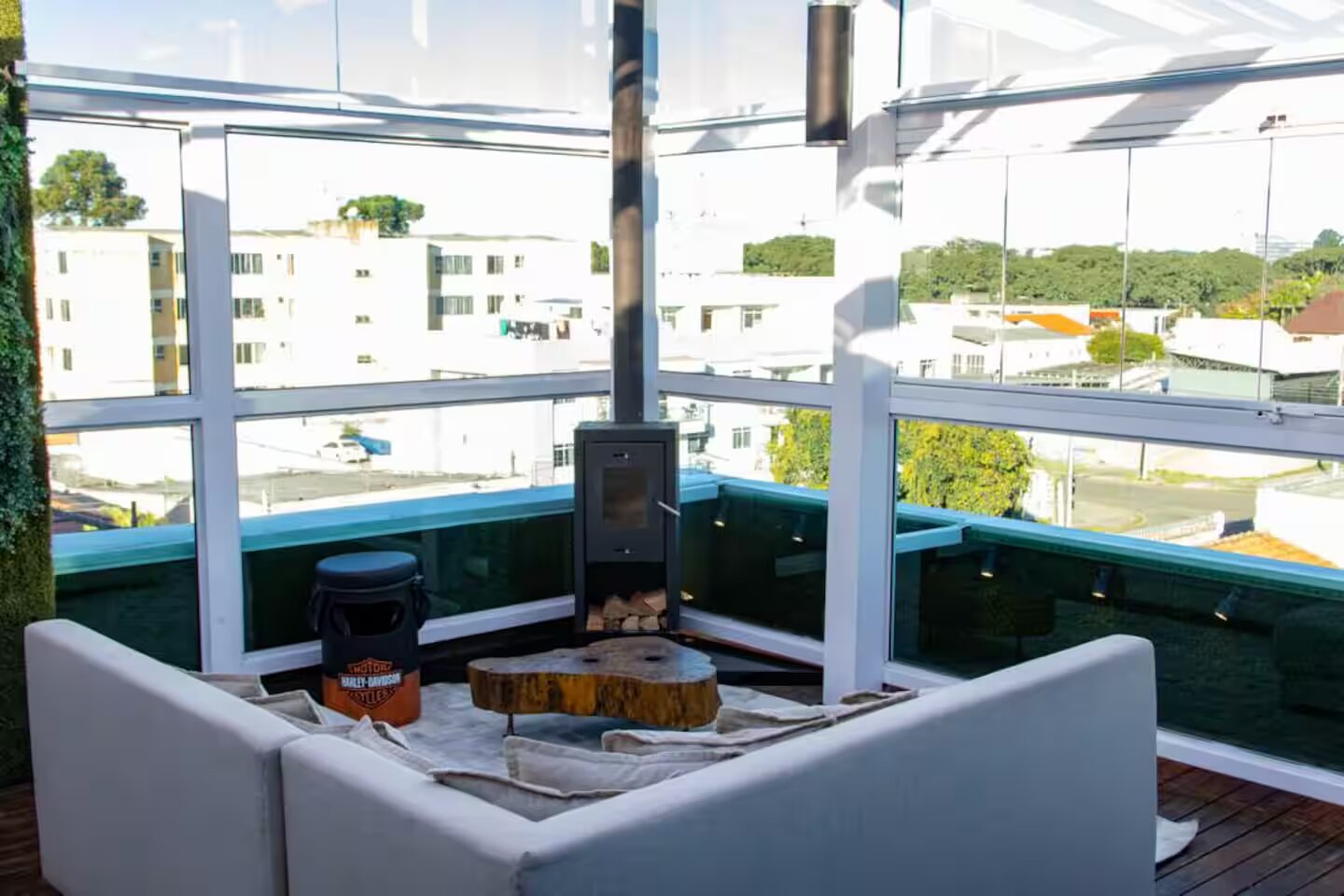 Lareira com tronco decorativo em área envidraçada de cobertura mobiliada em Curitiba, evidenciando o conforto e o estilo do imóvel no bairro Rebouças.