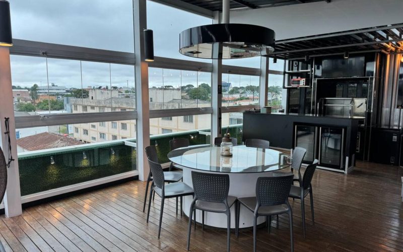 Mesa redonda para seis pessoas em espaço gourmet envidraçado de cobertura no Rebouças, perfeita para jantares e encontros em uma cobertura para alugar em Curitiba com vista panorâmica.